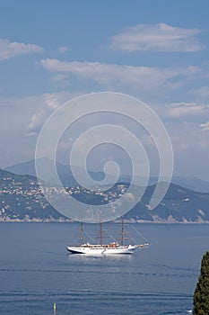 Luxury white sailboat in Portofino with sea, mountains, cliffs and villas.