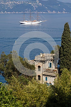 Luxury white sailboat in Portofino with sea, mountains, cliffs and villas.
