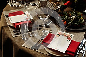 Luxury wine glasses and silver tableware near plates with red na