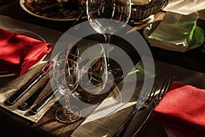 Luxury wine glasses and silver tableware near plates with red na