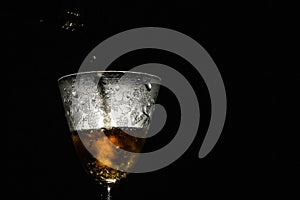 Luxury wine pouring in beautiful misted vintage glass on black background