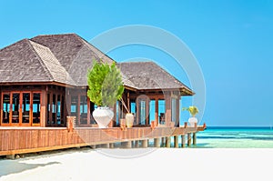 Luxury wooden house on stilts on the background of azure water and beautiful sunny sky