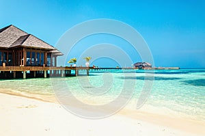 Luxury wooden house on stilts on the background of azure water and beautiful sunny sky