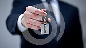 Luxury word on keychain in male hand, VIP hotel room for business client closeup