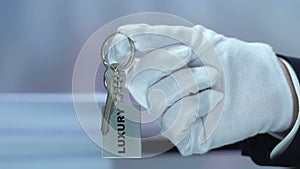 Luxury word on keychain in receptionist hand, high quality hotel, vip service