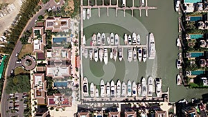 Luxury yachts docked by elegant villas in marina bay, top down aerial view.