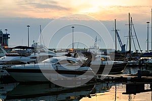 Luxury yachts docked in sea port at sunset. Marine parking of modern motor boats and blue water. Tranquility, relaxation