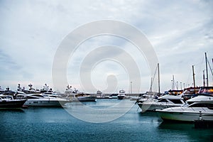 Luxury yachts docked in sea port at sunset. Marine parking of modern motor boats and blue water. Tranquility, relaxation