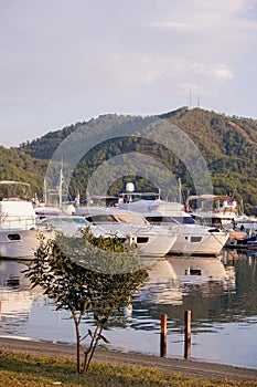 Luxury yachts docked in sea port at sunset. A stunning view of mega yachts in the port. Mountains background.