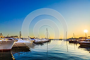 Luxury yachts, sailing and motor boats docked in sea port at sunset. Marine parking of modern motorboats, blue water. Travel.