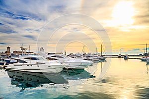 Luxury yachts at sunset. Marine dock of modern motor and sailing boats in sunshine, blue water sea, rainbow with sun.