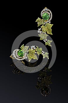 luxury yellow gold earrings with green demantoids and diamonds  on black background with reflection