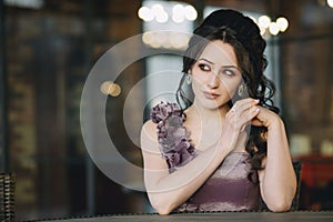 Luxury young woman with purple dress holding hands sitting in street cafe