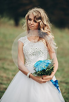 Luxuty portrait of blonde bride with bridal bouquet in autumn