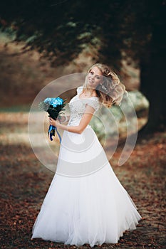 Luxuty portrait of blonde bride with bridal bouquet in autumn