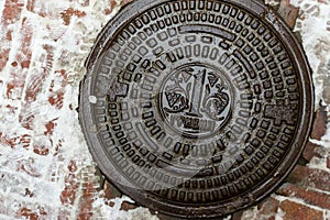 Lviv, Ukraine - January 22, 2019: Old, rusty manhole cover. On the hatch cover in the center there is an image of one