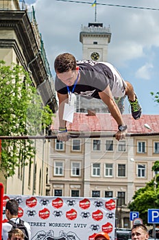 LVIV, UKRAINE - JUNE 2016: Young boy athlete demonstrates his ability by performing different exercises and figures on the horizon