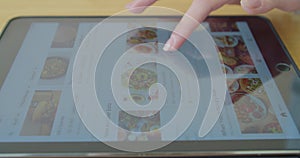 LVIV, UKRAINE - March 5, 2020: Woman orders food home in an online store using a PC tablet. Close-up.