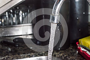 lwater coming out of the tap with dark background, copy space and focus on the water