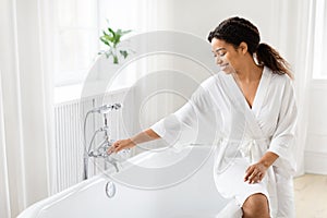ly reaching for bath faucet in robe