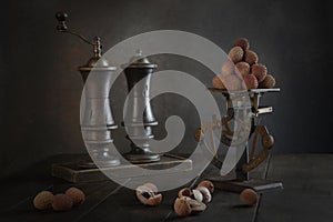 Lychees are on scales. Old scales.Still life with lychee fruit. Vintage wooden large appliances for salt and pepper.