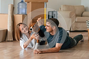 Lying down on the floor. Young couple with dog are moving to new home