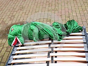 Lying dragon: green dragon outfit laying on the street in Amsterdam