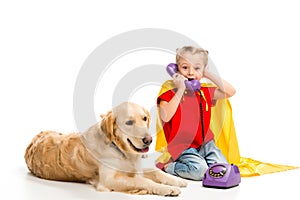 Lying golden retriever  with shocked little supergirl talking on phone