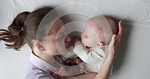 Lying loving mom gently strokes head of her sleeping baby