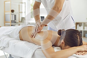 Lying woman patient getting massage of back from professional chiropractor or masseur