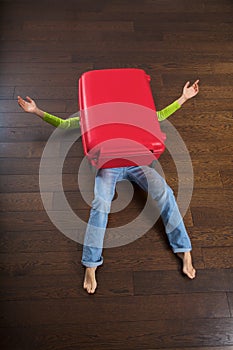 Lying woman under red suitcase