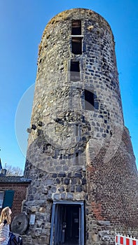 MÃ¼hlenturm Schloss Liedberg. Old historic stone tower in a German village. Remains of an old castle or city wall. A woman with a