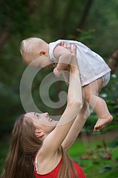 Mother playing with newborn baby on nature background. Happy motherhood concept. Vertical frame photo