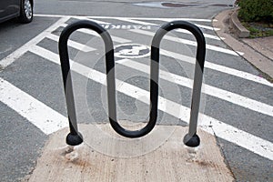 M-shaped black metal bike rack in parking lot