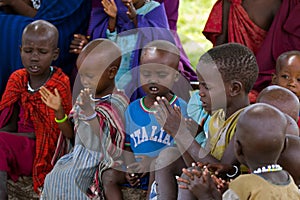 Maasai African kids singing a song under Acacia tree as outdoor school in Tanzania, East Africa