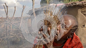A maasai warrior starts fire the traditional way at a manyatta in kenya
