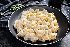 Mac and cheese. American style macaroni pasta in cheesy sauce. Black wooden background. Top view