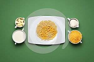 Mac and cheese ingredients on a green table. Cheese macaroni making of, top view
