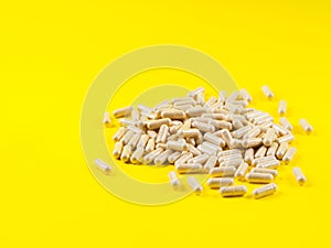 Maca powder in capsules on yellow background
