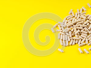 Maca powder in capsules on yellow background