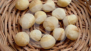 Macadamia, Hawaii nut in a wicker rattan bowl close-up top view.