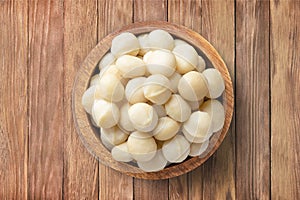 macadamia nuts peeled in bowl on wooden table background, top view. organic vegetarian food