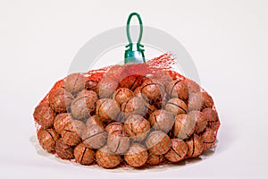 Macadamia nuts in a red mesh bag on a white background