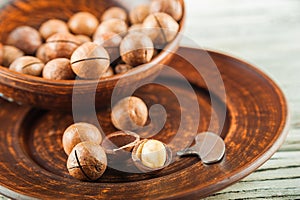 Macadamia nuts on a wooden plate on a white textural table closeup and copy space