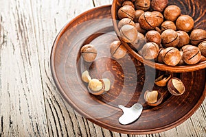 Macadamia nuts on a wooden plate on a white textural table closeup and copy space