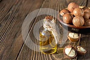 Macadamia oil bottle and macadamia nuts on wooden background