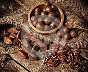 Macadamia, Pecan and Pili nuts on wooden table photo