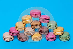 Macaron pyramids. Close-up of colourful French macaroons in shape of a pyramid on a blue background. Pastries, desserts and sweets
