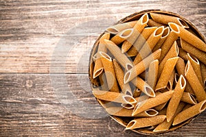 Macaroni on the bowl, wooden background.