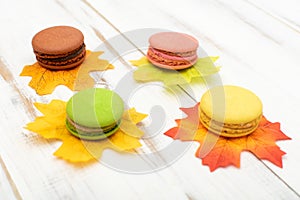 Macaroni cakes and autumn leaves on a wooden background